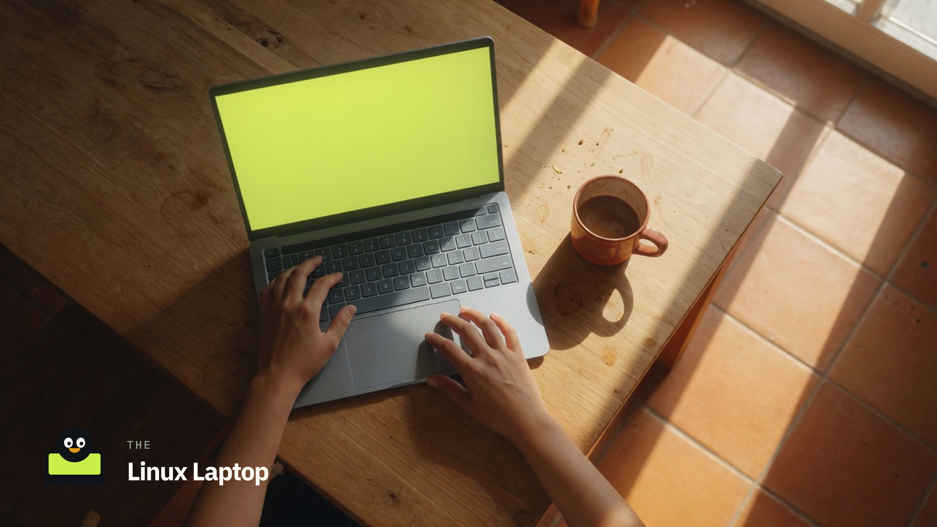 Overhead photo of hands on a silver laptop with a lime screen at a sunlit wooden table, The Linux Laptop mark in the corner